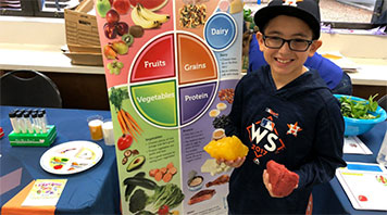 Image of boy standing in front of healthy eating banner