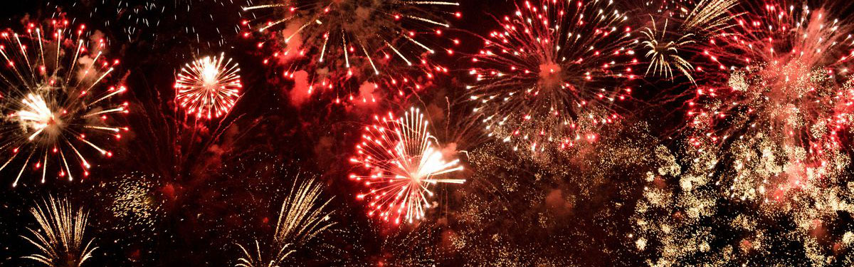 photo of colorful fireworks going off in dark night sky.