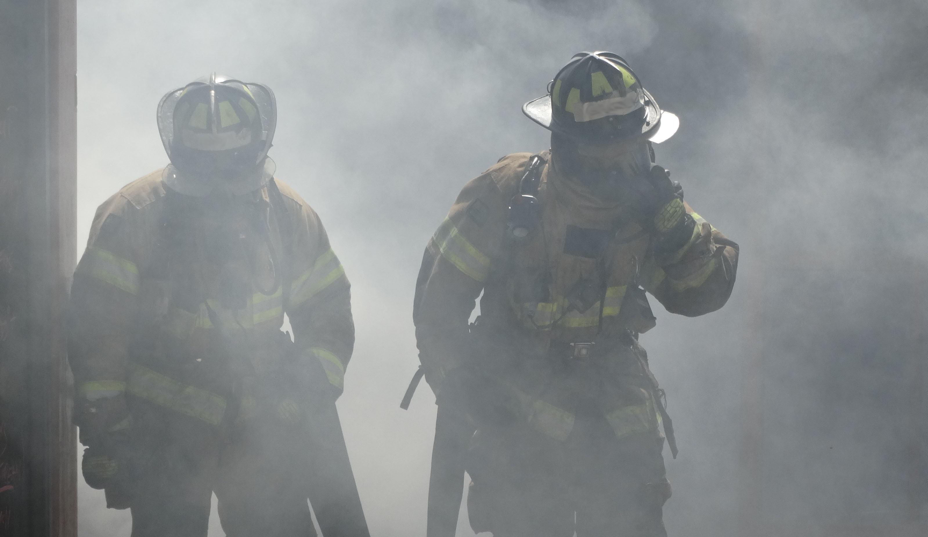 two firefighters walking through smoke in gear